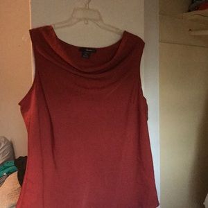 Sleeveless rust colored blouse.